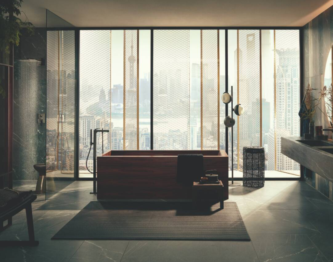 Luxury spa bathroom with AXOR MyEdition floor-standing bath tap, freestanding wooden bathtub, and floor-to-ceiling city views