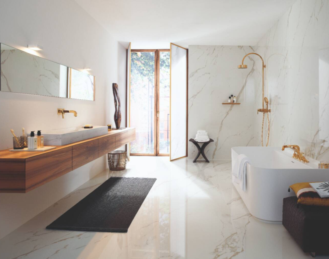 Luxury bathroom featuring AXOR Montreux gold taps and shower system with a floating wood vanity and white marble walls