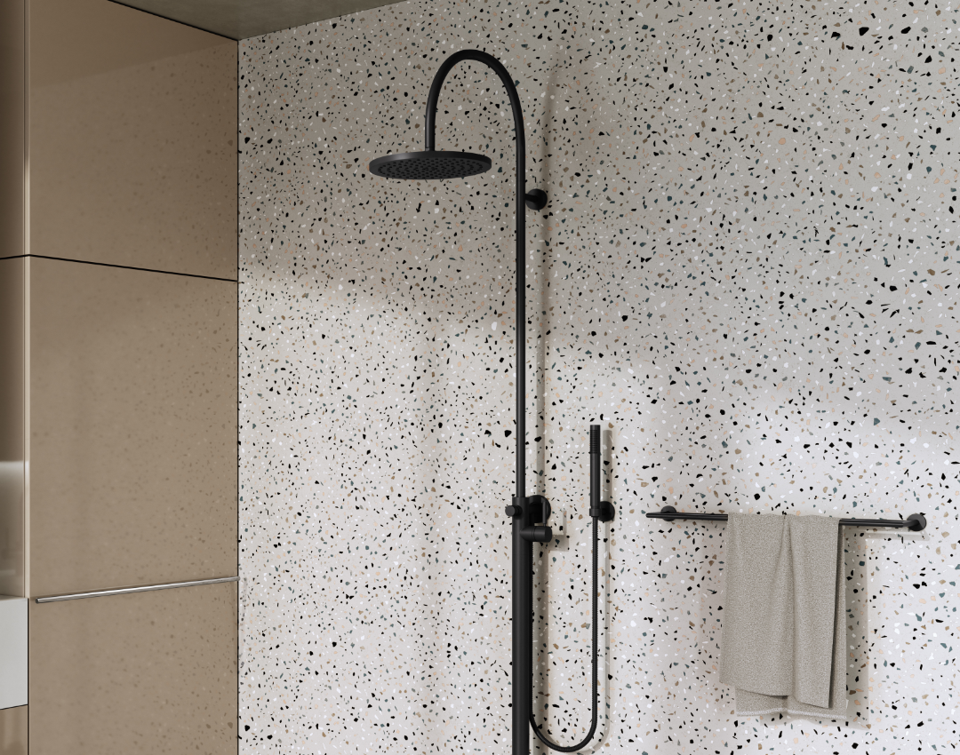 Dornbracht Tara black matte shower system with a tall arched neck rainfall shower head and matching hand spray, set against a terrazzo-style tiled wall.