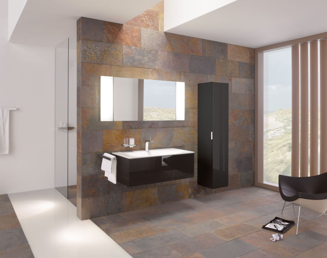 Keuco Edition 400 black high-gloss wall-hung vanity unit and matching tall side cabinet, featuring an illuminated mirror and chrome basin tap against a slate-tiled wall.